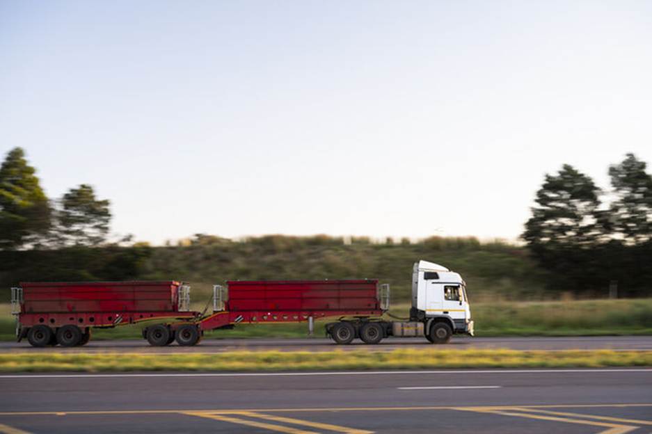 A large truck carries a double trailer, possibly hauling cargo that could be improperly loaded or secured
